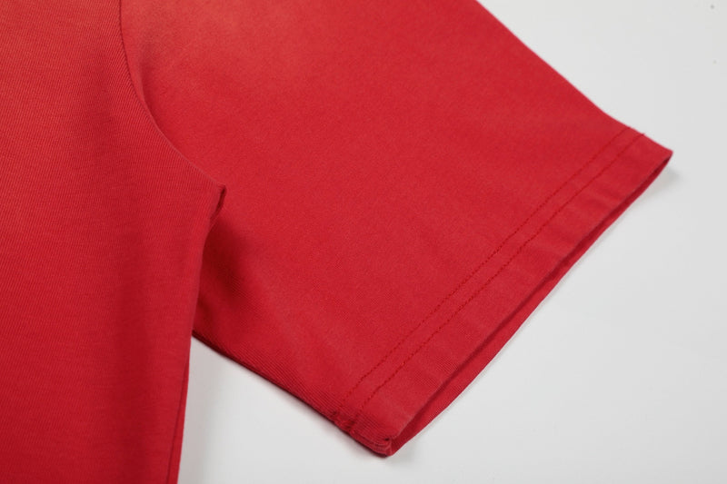 Close-up of a red distressed graphic tee sleeve with stitched cuff on a white background