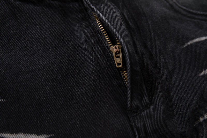 Close-up of brass zipper detail on washed black denim jeans