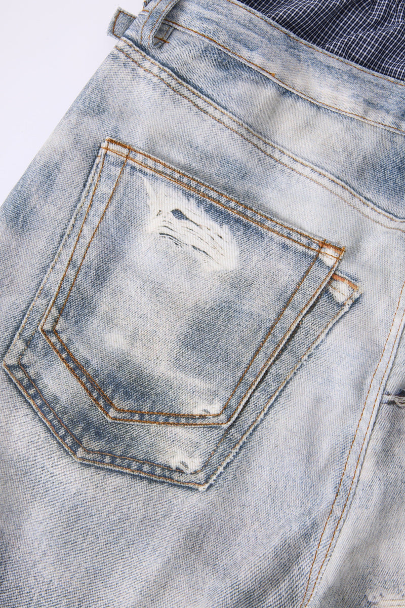 Back pocket close-up on light wash distressed jeans with layered waistband