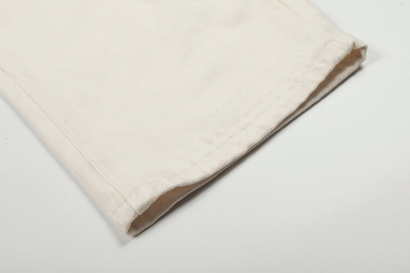 Close-up of cream denim pant hem with visible seam stitching