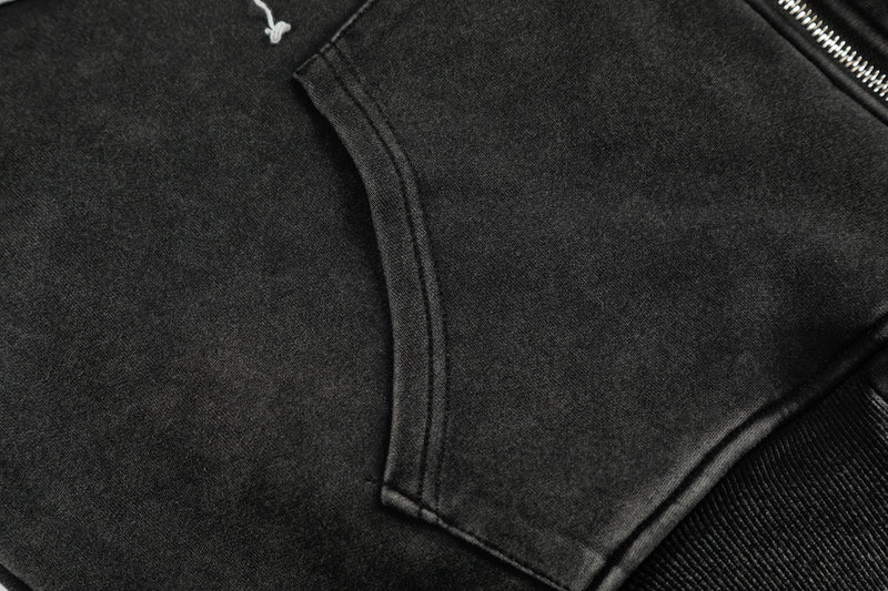 Close-up of black hoodie front pocket seam and zipper beside ribbed cuff