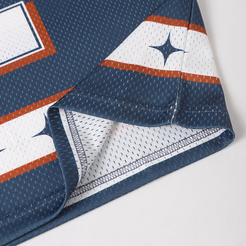 Close-up of a navy mesh football jersey hem with white star stripe trim and orange accents
