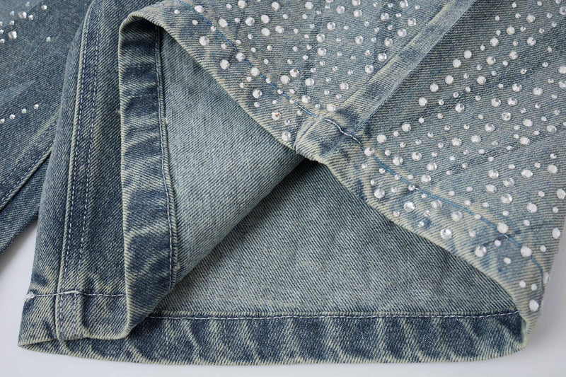 Close-up of light wash denim shorts side seam and rhinestone-studded fabric