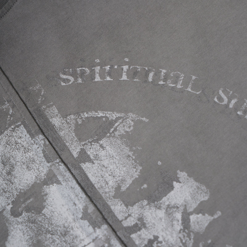 Close-up of distressed printed text and portrait detail on washed grey tee