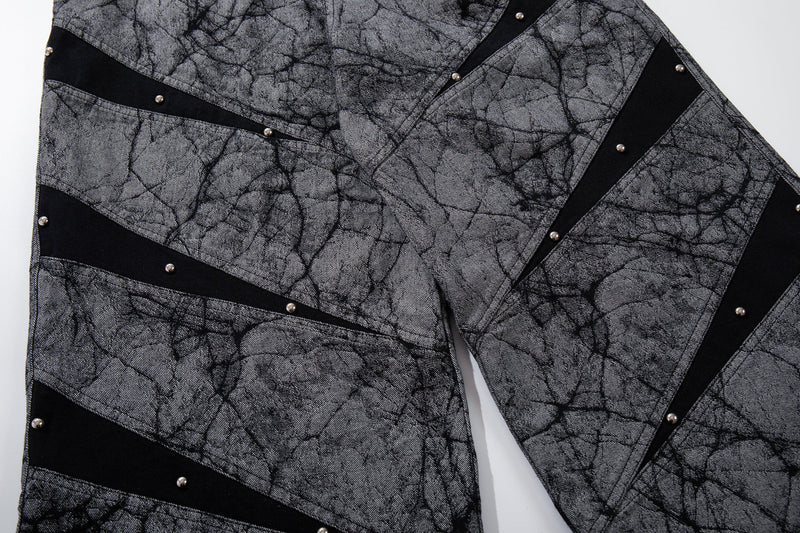 Close-up of angled panel stripes and rivet studs on gray denim pants