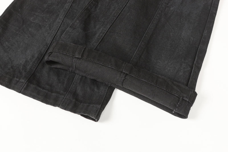 Close-up of black jean hem with folded cuff and stitched seam detail