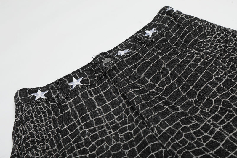 Close-up of black pants waistband with star embroidery and button detail