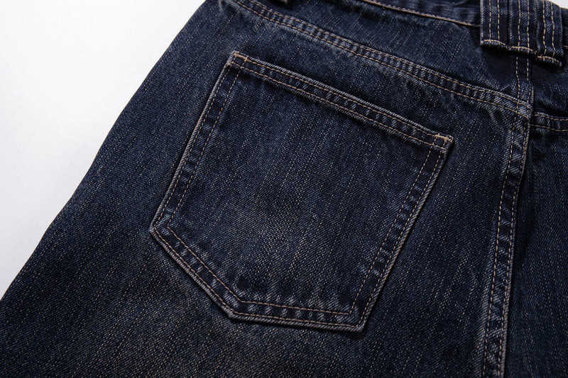 Close-up of a back patch pocket on dark wash denim with contrast stitching