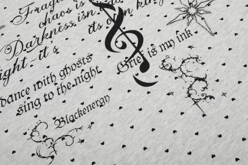 Close-up of a white graphic tee with black script text, dotted pattern, and large treble clef print