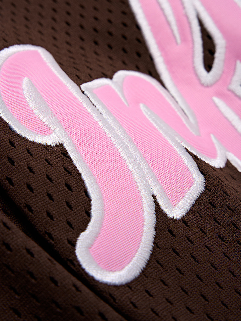 Close-up of brown mesh jersey with pink chenille varsity lettering and white trim on the front