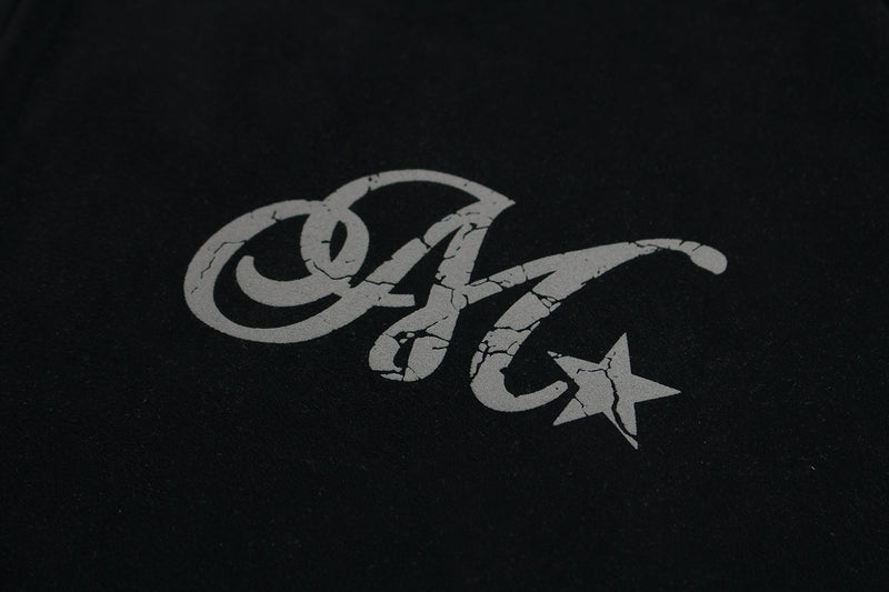 Close-up of decorative gray script and star graphic on black hoodie chest