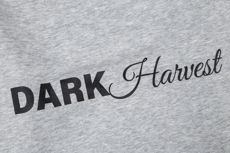Close-up of black Dark Harvest text printed on heather gray fabric