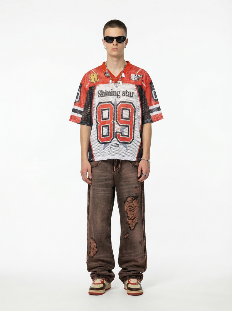 Model wearing a red and black mesh football jersey with Shining Star 89 graphic, distressed brown jeans, and sunglasses
