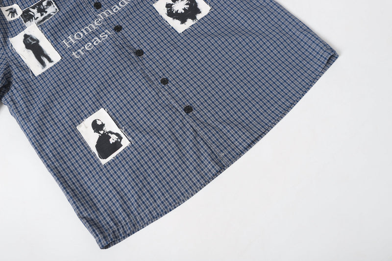 Angled front view of blue plaid overshirt with graphic patches and button placket