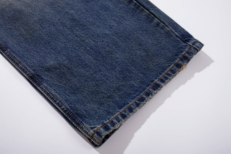Close-up of jean cuff with dark blue denim and raw frayed edge