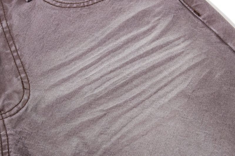 Close-up of brown denim front leg with faded whisker marks
