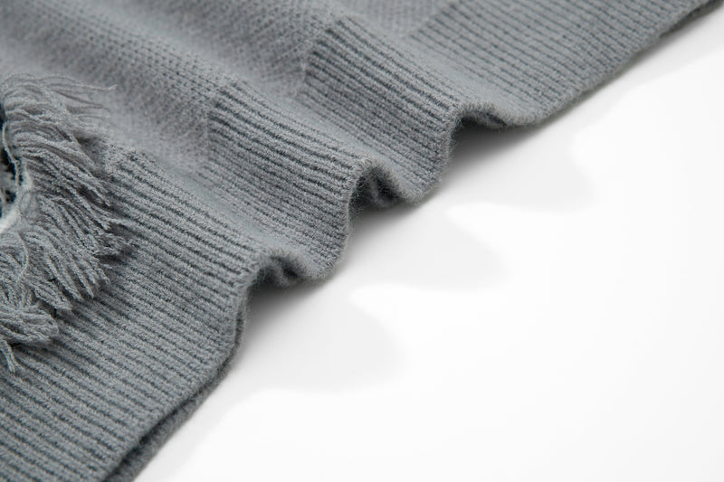 Gray knit sweater close-up of sleeve cuff and fringe patch edge