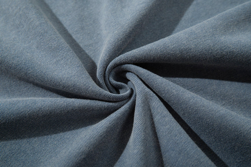 Close-up of faded blue vintage washed T-shirt fabric with a soft twisted knit texture and streetwear look