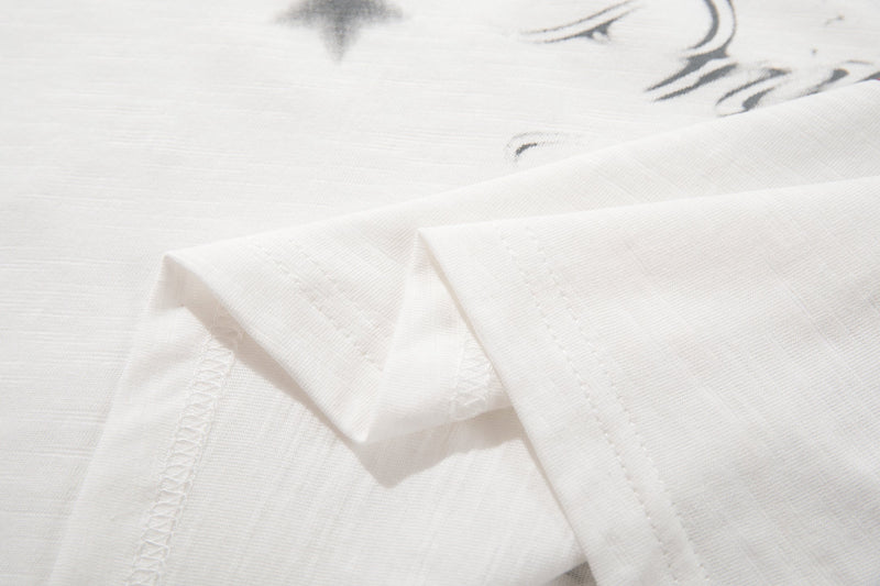 Close-up of a white cotton streetwear T-shirt with subtle black graphic print and visible stitched hem detail