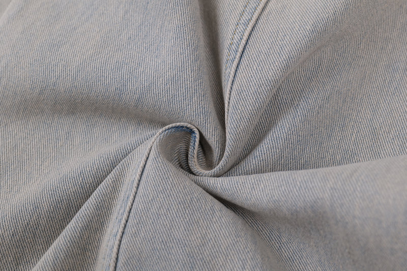 Close-up of light wash denim fabric with visible twill weave and curved seam