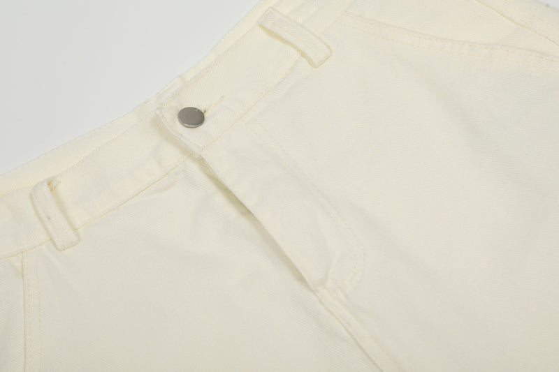 Close-up of cream cargo pants waistband snap button and front seam detail