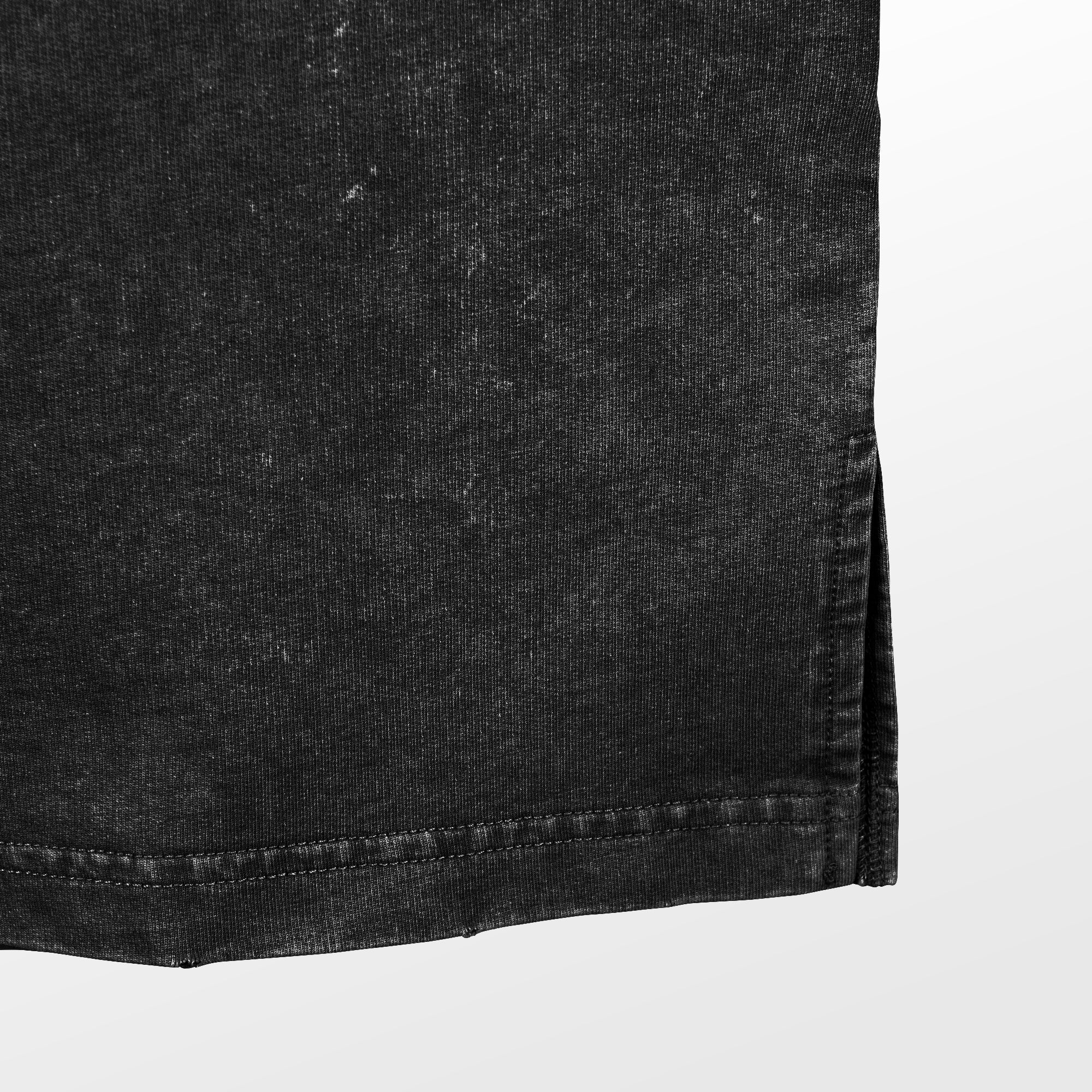 Close-up of the hemline of a Solo Leveling Vintage Anime Graphic Tee in black denim with a faded look. It features a vertical slit and visible stitching along the hem against a light gray gradient background.