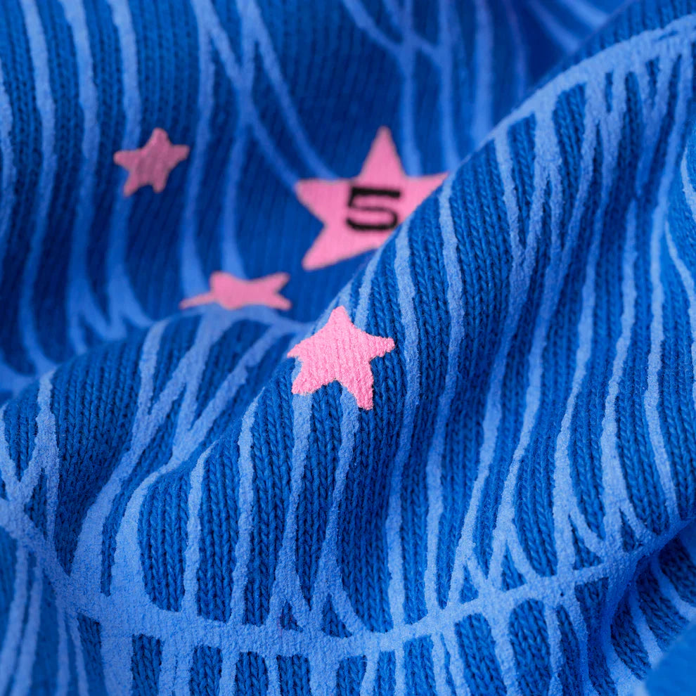 Close-up of blue 440GSM heavyweight cotton fleece with light blue lines and pink stars, including a “5,” highlighting the soft, streetwear style of the Sp5der “555” Hoodie – Royal Blue Spider Web Pullover.