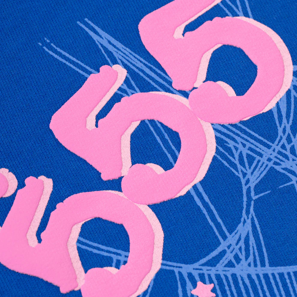 Close-up of the Sp5der “555” Hoodie – Royal Blue 440GSM Heavyweight Spider Web Streetwear Pullover, featuring three pink abstract shapes layered diagonally with white sketch-like lines and a small pink star in the background.