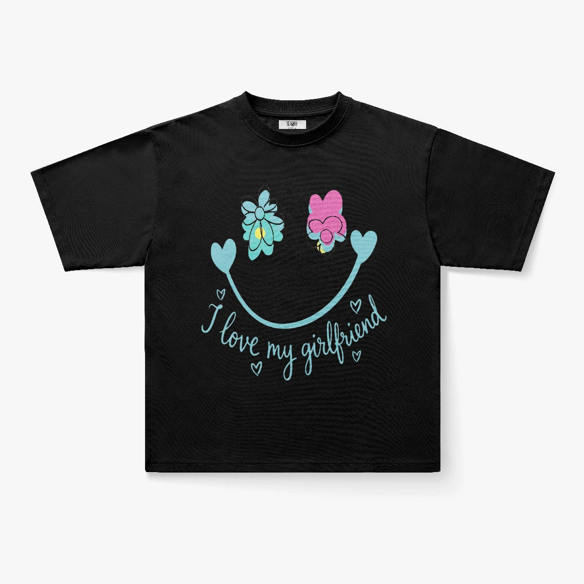 The I Love My Girlfriend Smiley Face Floral Graphic Oversized T-Shirt is a black tee with two cartoon flowers (blue and pink), a curved blue smiley face with hearts, and "I love my girlfriend" written in blue script with heart accents.
