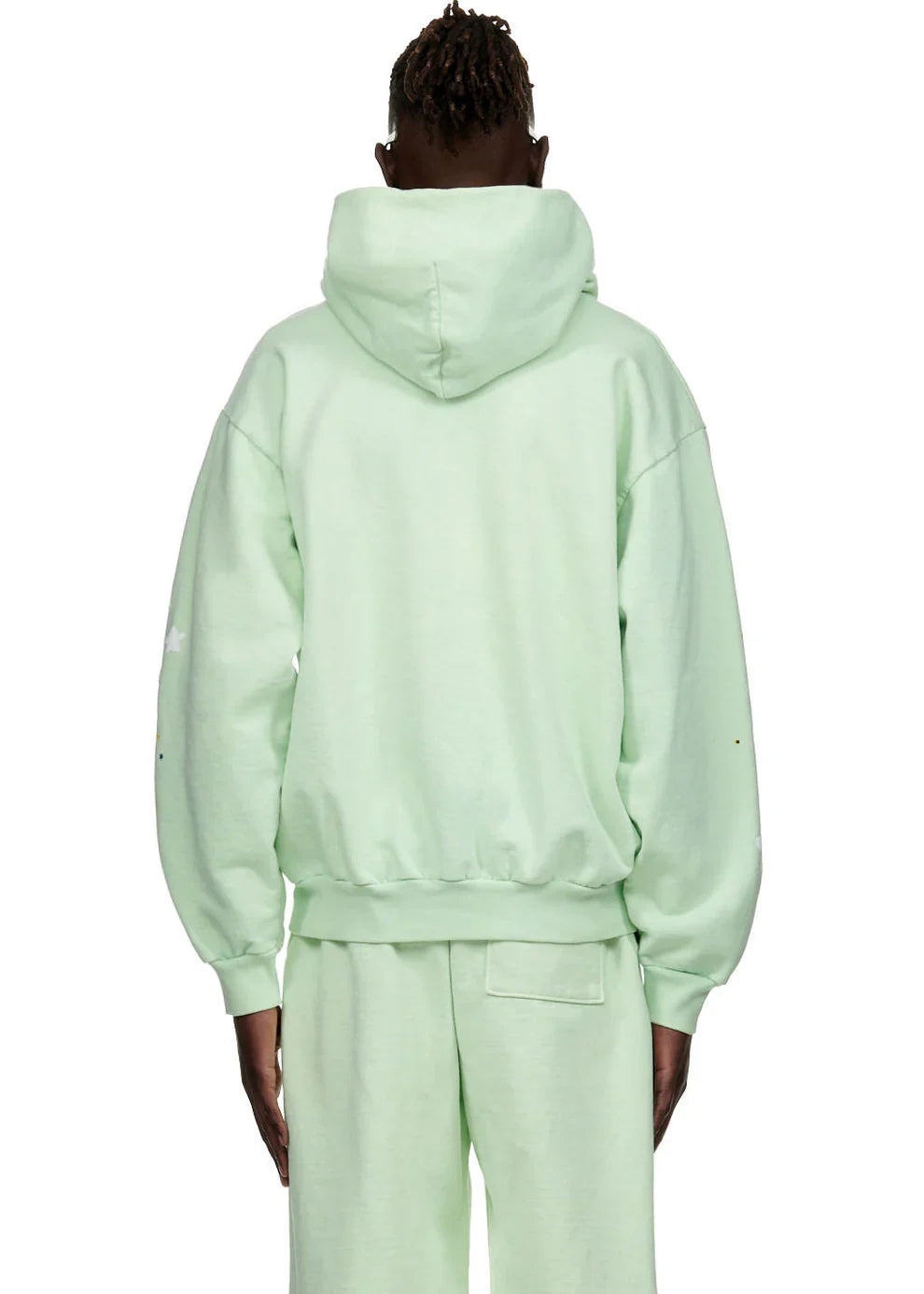 Wearing a Sp5der “Mint Star Web” Hoodie in mint green, a person stands facing away from the camera with arms relaxed, showcasing this 440GSM heavyweight oversized streetwear pullover inspired by Y2K style.