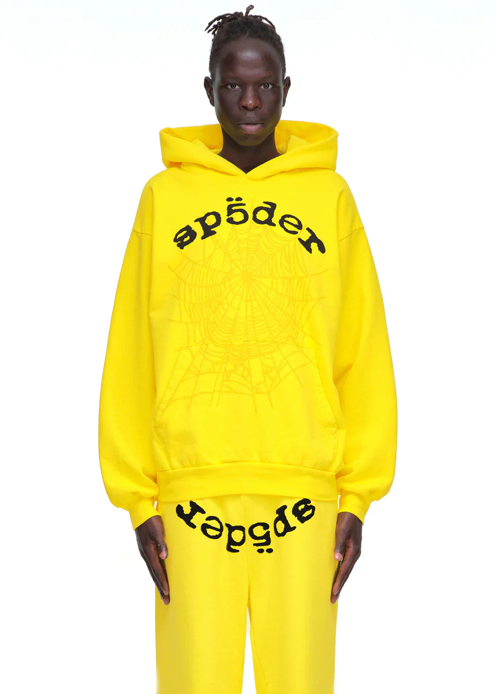 A person wears the Yellow Graphic Hoodie with Spider Web Print and Lettering – Comfort Fit Pullover Hoodie and matching pants, featuring black graffiti-style "spēder" text, standing against a plain white background.