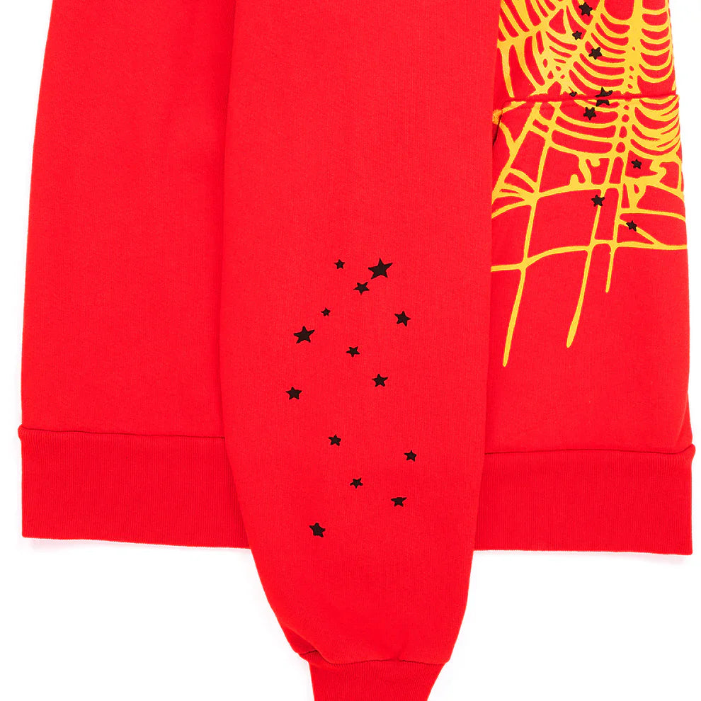 The Red Graphic Hoodie with Spider Web Print and Star Details is a comfort fit pullover featuring a yellow spiderweb graphic and scattered black star accents near the cuff, perfect for streetwear style.