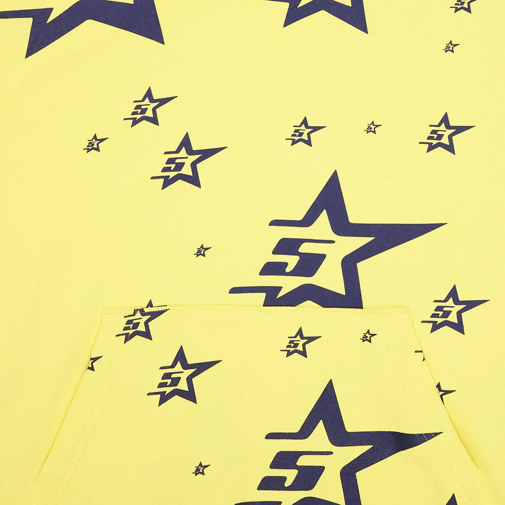 The Yellow All-Over Star Graphic Hoodie – Comfort Fit Pullover features navy blue star prints, each with a stylized S and J, in varying sizes scattered across the fabric and kangaroo pocket.