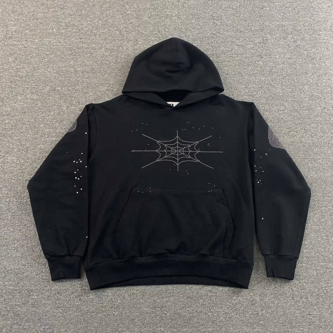The Sp5der Black Rhinestone Spiderweb Crystal Hoodie features a striking crystal spiderweb on the chest and small rhinestone dots on the sleeves, displayed flat on a gray background for a perfect streetwear look.