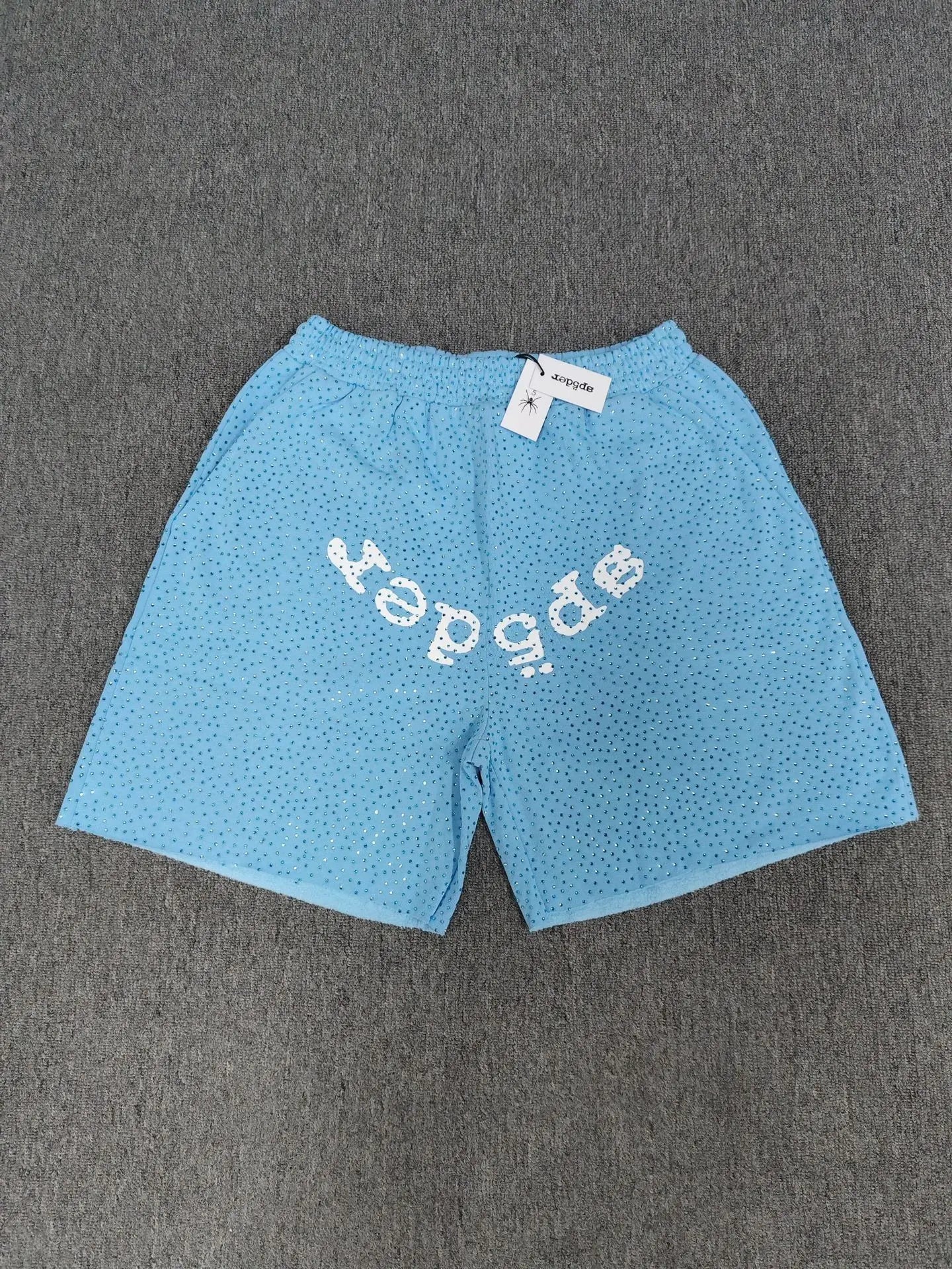 Light blue Sp5der jogger shorts with white arched logo and all-over rhinestone detailing
