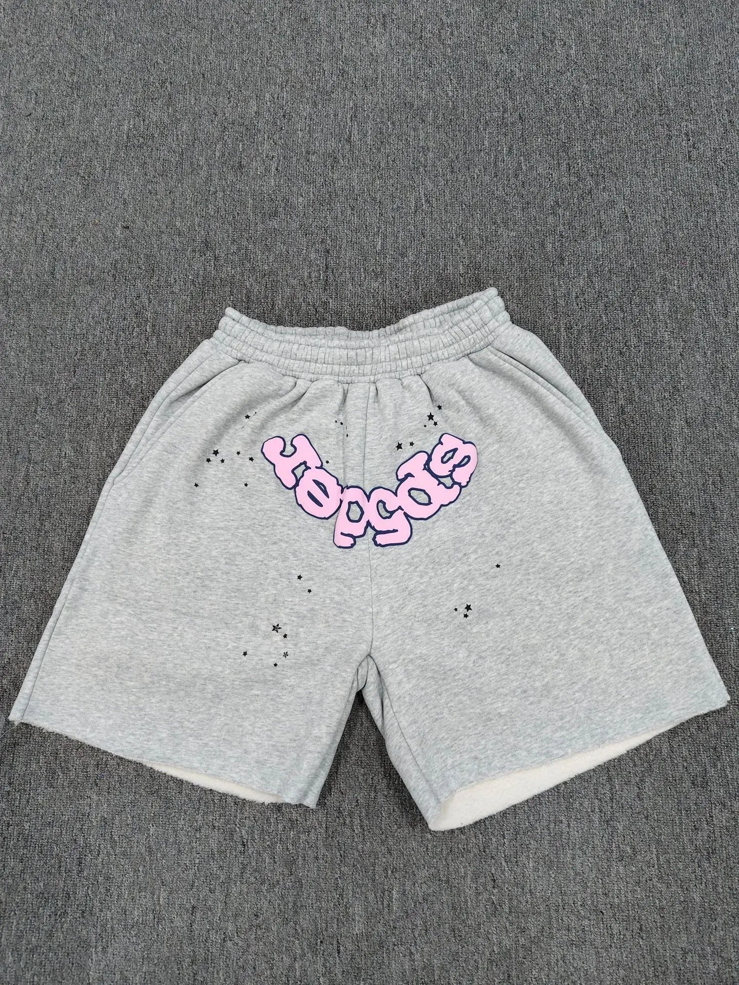 Sp5der light grey jogger shorts with pink bubble letter graphic and star print on front