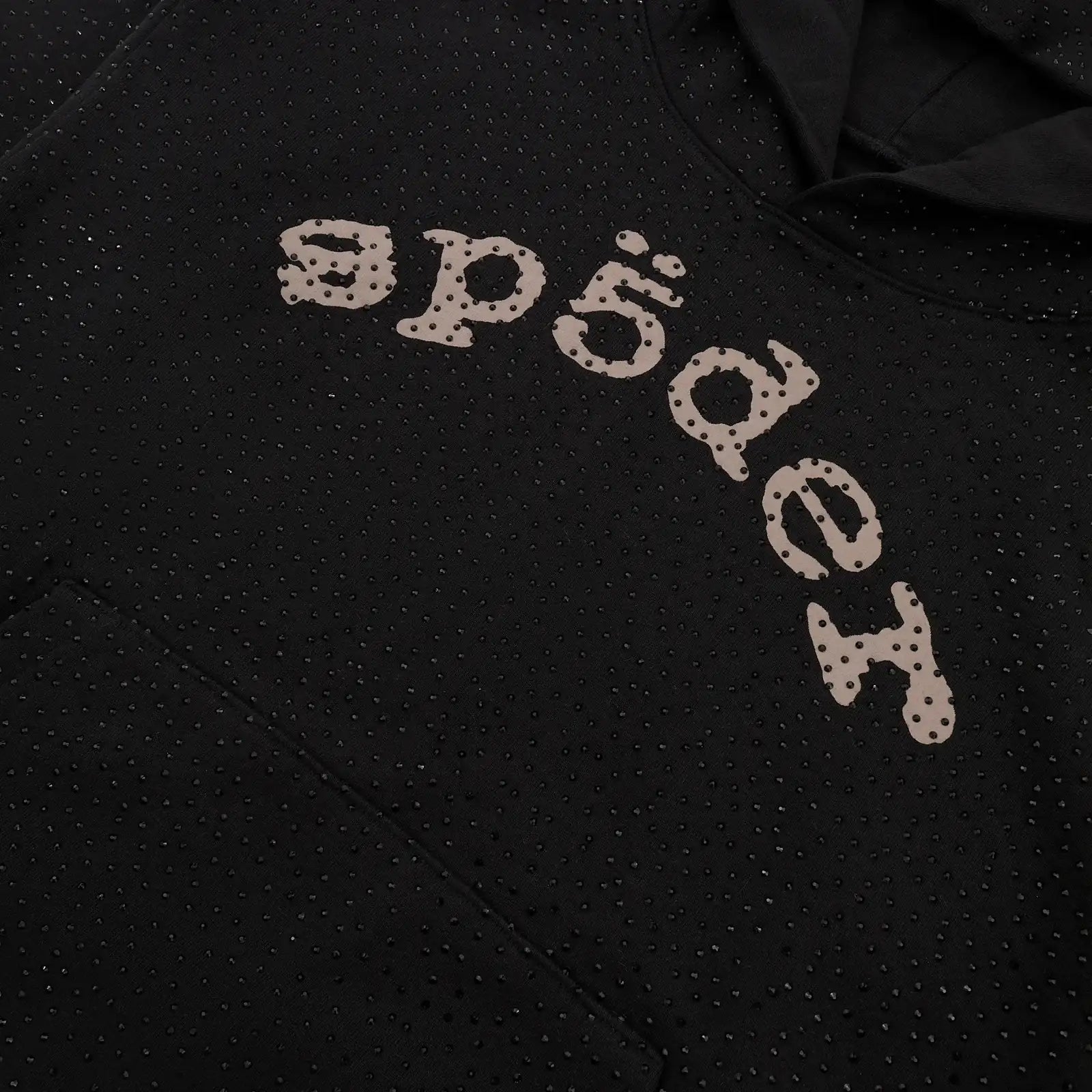 A close-up of the Black Sp5der Rhinestone Logo VVS Hoodie 440GSM showcases all-over black crystals and large, stylized "sp5der" lettering across the chest, featuring small perforations in the design.