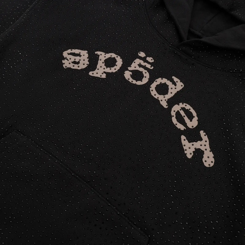 A close-up of the Black Sp5der Rhinestone Logo VVS Hoodie 440GSM showcases all-over black crystals and large, stylized "sp5der" lettering across the chest, featuring small perforations in the design.