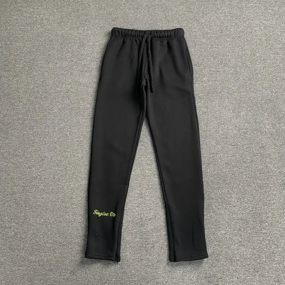 Black drawstring jogger pants with neon green script print on lower left leg