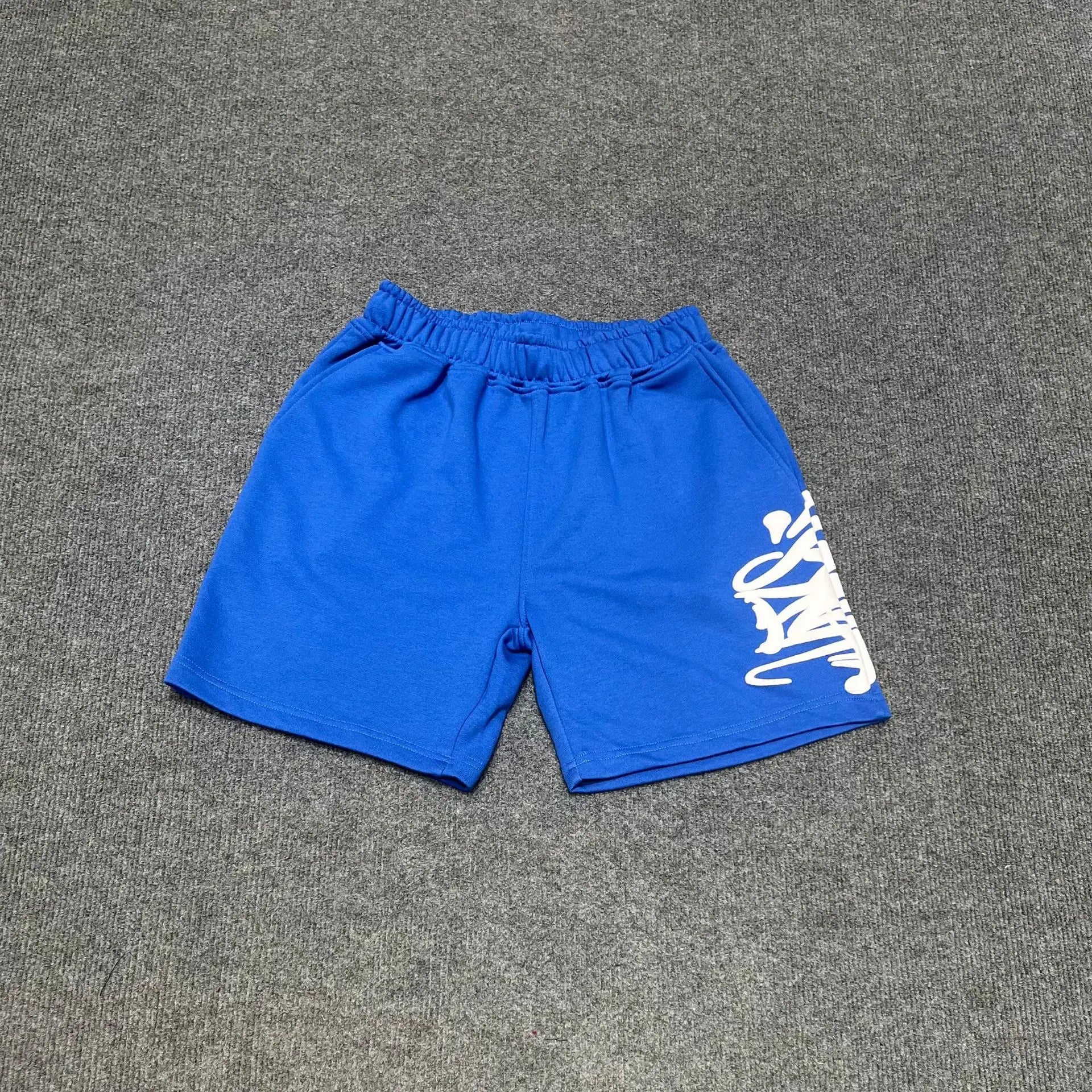 Blue cotton jogger shorts with white graffiti graphic print on the right leg, elasticated waistband