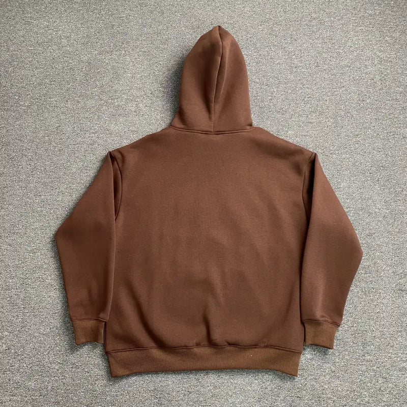 A Syna World Brown Graffiti Letter Print Oversized Hoodie is laid flat on a gray carpet, showcasing the back.