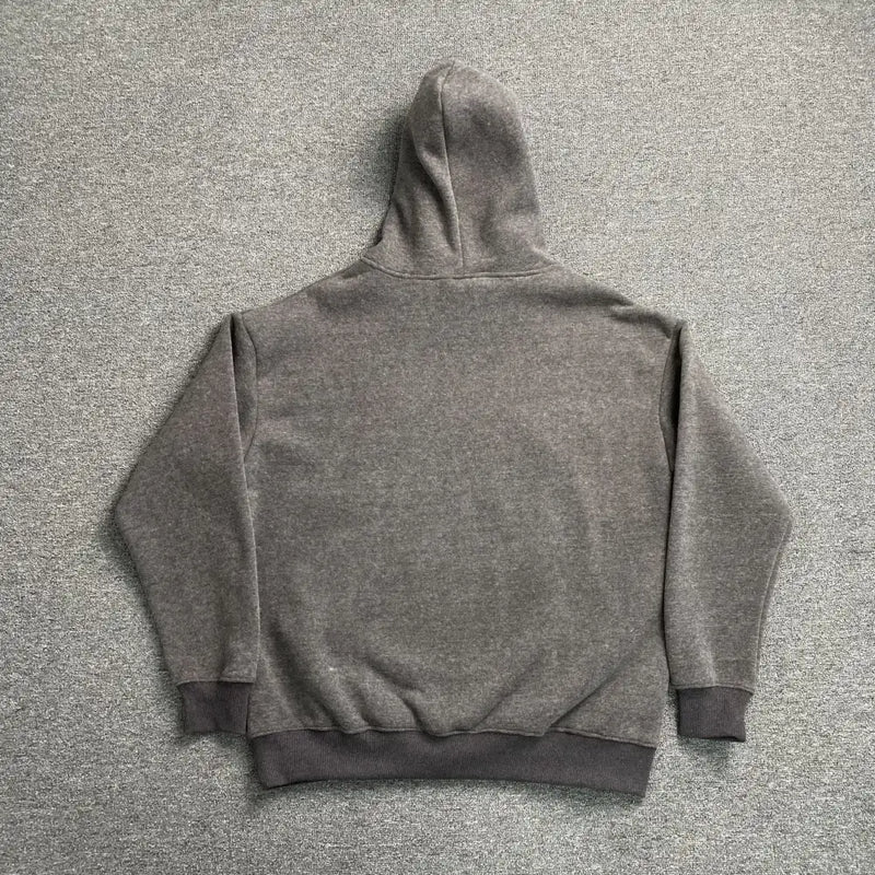 The Syna World Grey Graffiti Graphic Pullover Hoodie, laid flat face down on light grey carpet, showcases long sleeves and ribbed cuffs and hem—ideal for effortlessly upgrading your streetwear style.