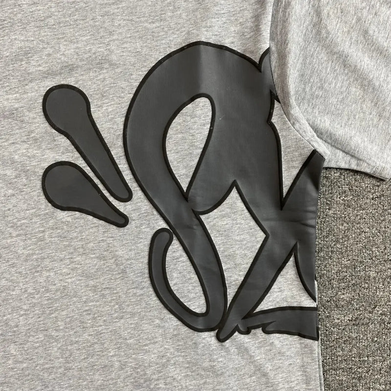 The Syna World Grey Letter Graphic Crewneck T-Shirt is made from 100% cotton and features a bold black abstract design with swooping lines and teardrop shapes across its oversized, heather grey surface.