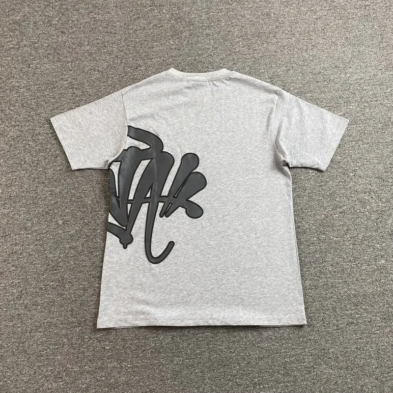 The Syna World Grey Letter Graphic Crewneck T-Shirt, made from 100% cotton, is heather grey with a bold black abstract graffiti-style design on the lower left back.
