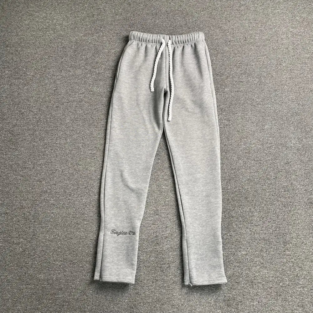 Syna World light grey drawstring jogger pants with script letter print on lower left leg, laid flat