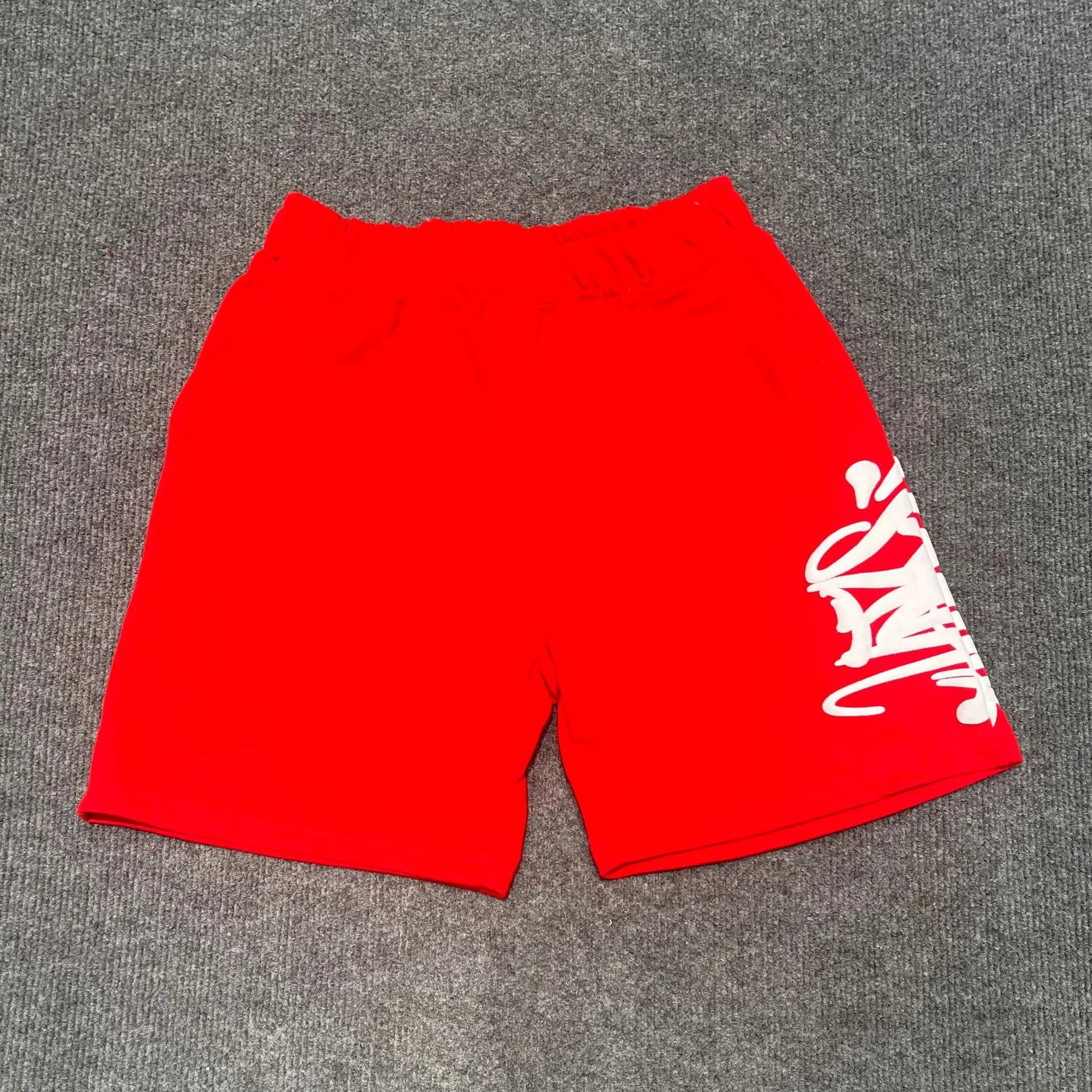 Red cotton jogger shorts with white graffiti script print on the right leg and drawstring waistband