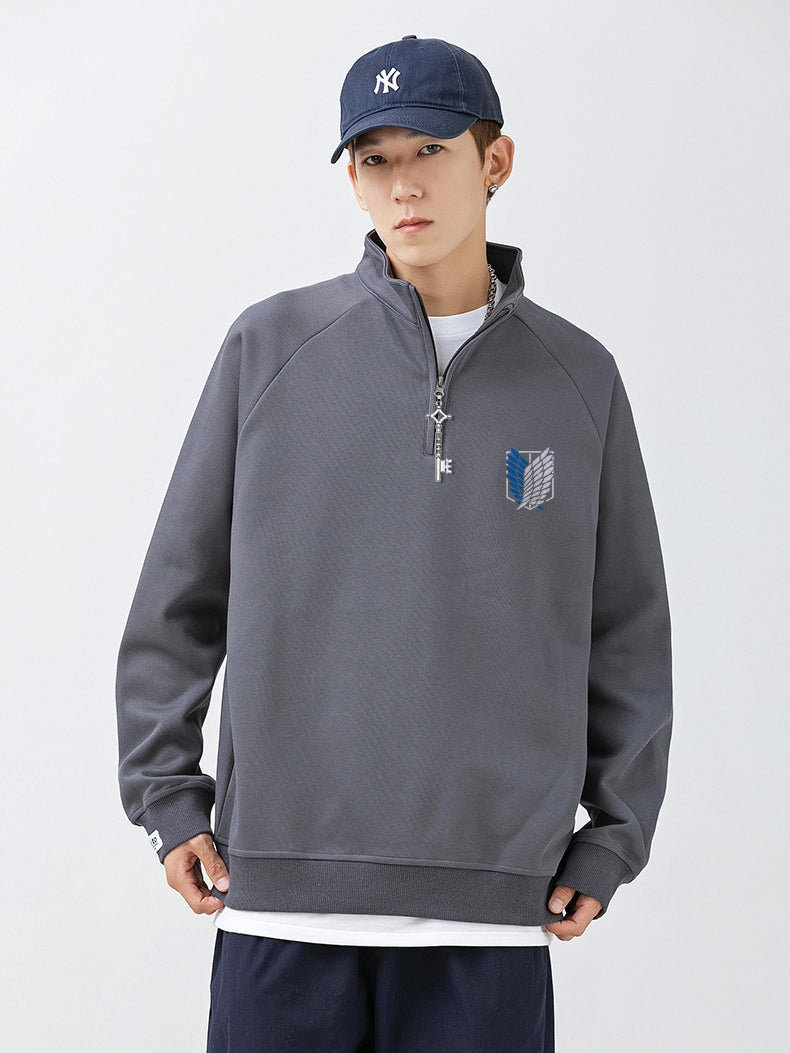 The individual wears a Limited Edition Attack on Titan Half-Zip Sweatshirt featuring Eren’s Key Zipper and the Scout Regiment Logo, paired with a white undershirt and navy pants. A navy baseball cap with a white logo completes the look against a plain white backdrop.