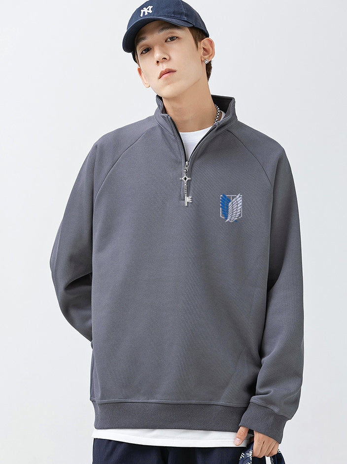 Against a plain backdrop, someone sports a navy cap and the Limited Edition Attack on Titan Half-Zip Sweatshirt featuring Eren’s Key zipper and Scout Regiment logo, paired with a white undershirt and dark pants.