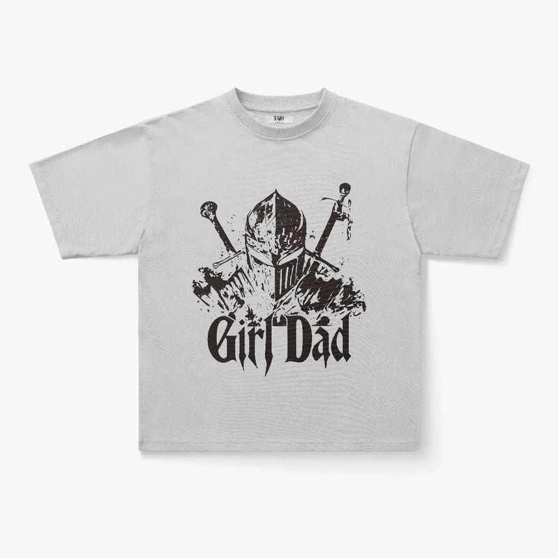 The Girl Dad Knight Armor Graphic Print Oversized T-Shirt in Sage Green features a medieval knight helmet with crossed swords and bold black lettering, made from vintage-washed cotton for a comfortable look.