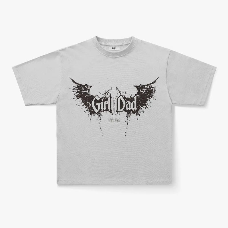 The Girl Dad Dark Wing Splatter Graphic Oversized T-Shirt features bold, wing-inspired graphics and stylized lettering on light gray heavyweight cotton—a must-have for gothic streetwear fans seeking comfort and style.